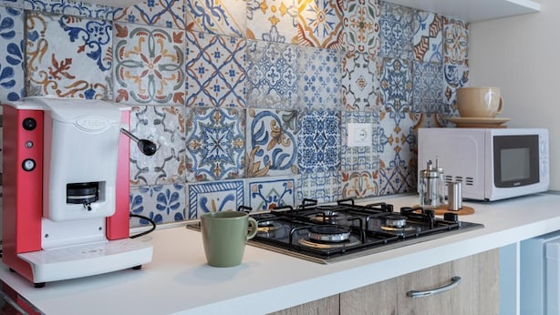 Une cuisine équipée d’une machine à café, d’une tasse, d’une cuisinière à gaz et d’un four à micro-ondes.