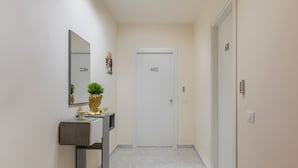 Un couloir avec une porte portant l’inscription « 602 » et un miroir placé sur une console, sur laquelle se trouve une plante.