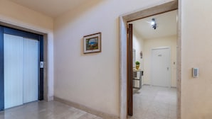 Un couloir avec une porte portant l’inscription « 602 », un tableau encadré accroché au mur et une plante en pot placée dans l’embrasure de la porte.