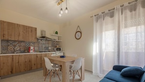 Une cuisine moderne avec des meubles en bois, une table à manger avec des chaises, un canapé bleu et une horloge au mur.