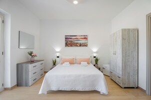 Un dormitorio con cama, mesitas de noche, armario y un cuadro de un paisaje urbano en la pared.