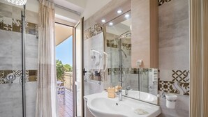 Un baño moderno con un lavamanos grande, cabina de ducha de vidrio y vista al patio exterior.