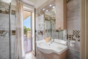Un baño moderno con un lavamanos grande, cabina de ducha de vidrio y vista al patio exterior.