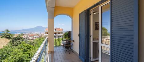 A balcony with a table and chairs, a sliding door, and a view of a city and mountain.