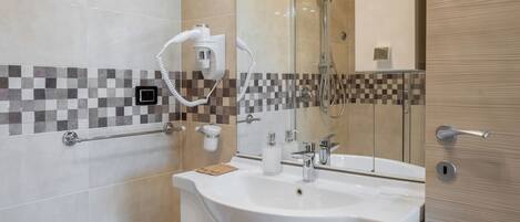 A modern bathroom with a large mirror, a sink, and a shower area.