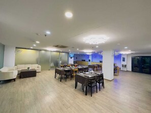 A spacious room with a dining area, a sofa, and a television. - Hotel Aarkay Palace (Noida)