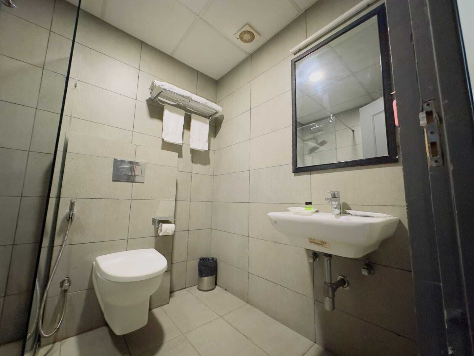 Un bagno piccolo rivestito di piastrelle, con il water, un lavandino e una doccia.