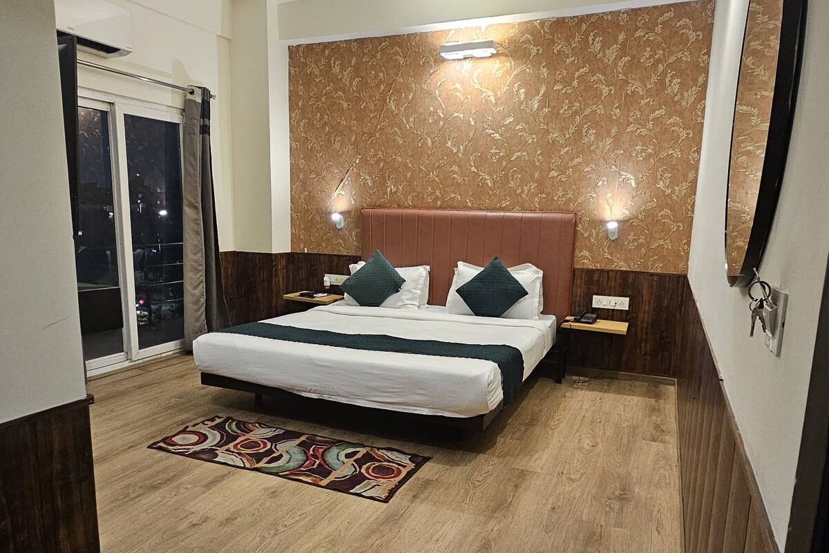 A bedroom with a bed, a ceiling fan, a nightstand, a mirror, and a window with curtains.