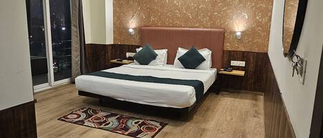 A bedroom with a bed, a ceiling fan, a nightstand, a mirror, and a window with curtains.