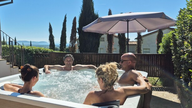 Een jacuzzi met vier personen, omringd door een houten omheining, een trap en een uitzicht op verre bergen.