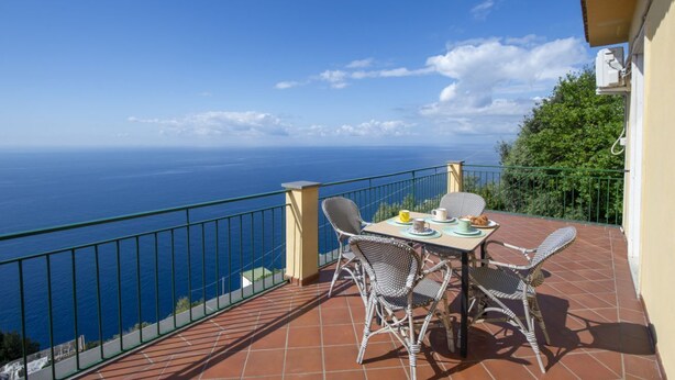 A terrace with wicker chairs and a table, overlooking a coastal view. - VivimiHome-Casa Tiberio (Conca dei Marini)