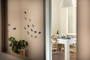A dining area with a white table set for two, a bottle of wine, and a plant. - Casa Tirreno: Spacious Seaside Apartment with Private Parking & Balcony (San Vincenzo)