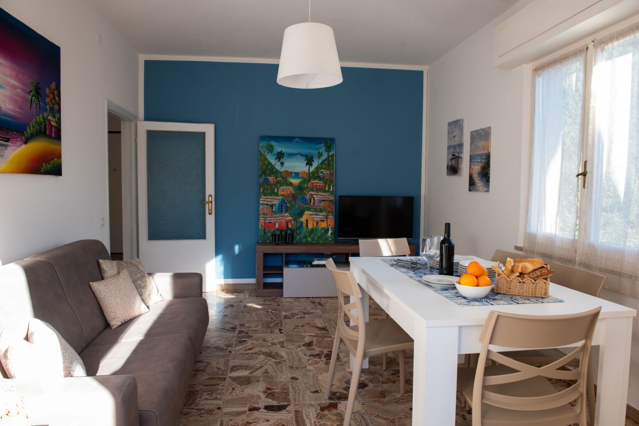 A modern living room with a sofa, dining table, and artwork on the walls.