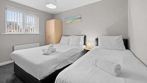 Una habitación de hotel con dos camas, un armario de madera, un cuadro en la pared y una ventana con persianas.