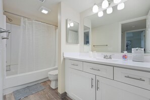 Casa de banho moderna com cabine de duche, sanita, lavatório com espelho e porta-toalhas.