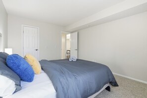 Quarto com cama, almofadas e uma porta.