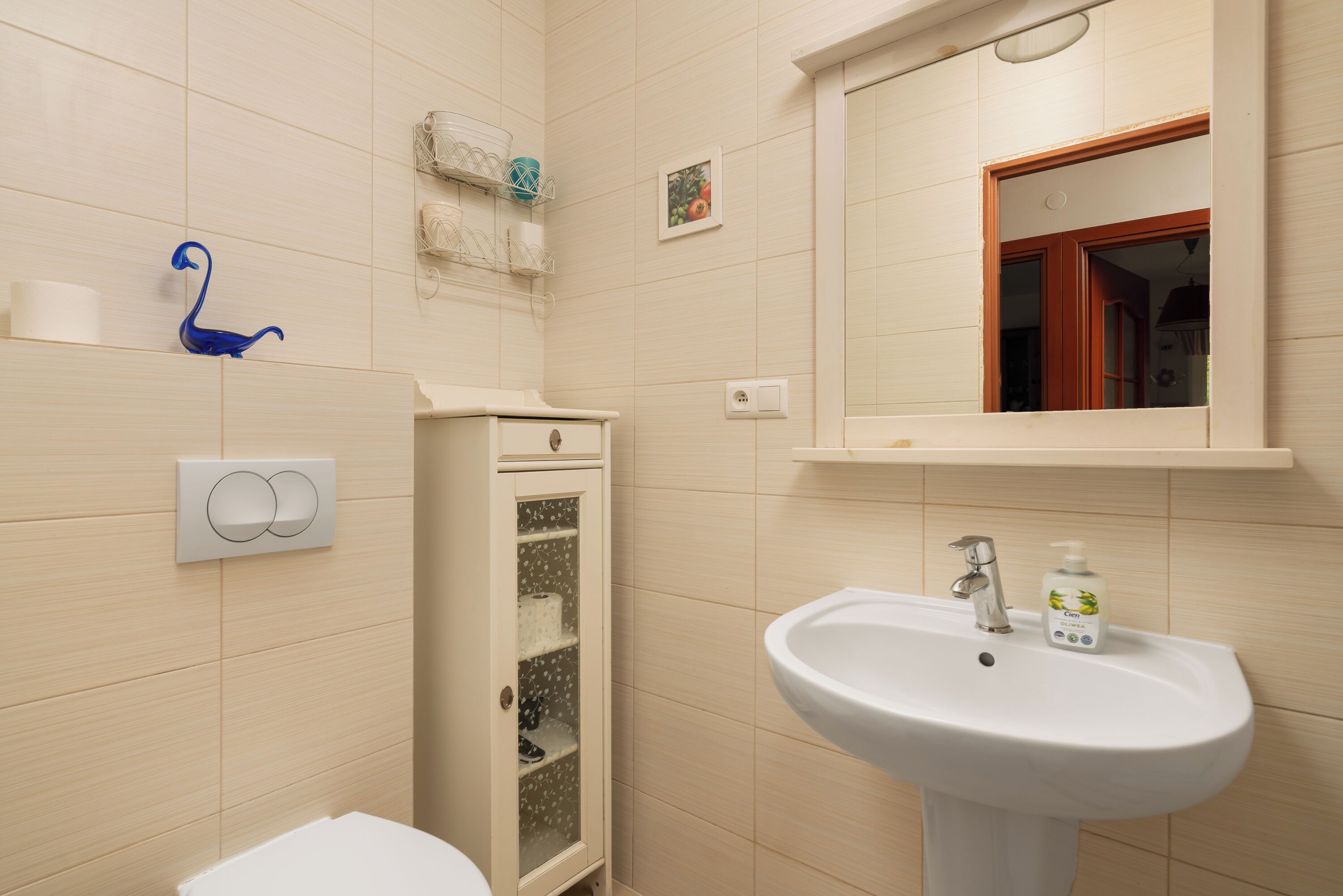 A bathroom with a white sink, a toilet, and a cabinet with glass doors.