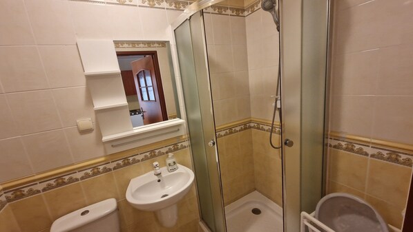 A bathroom with a glass-enclosed shower, a sink, and a toilet.
