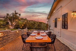 An outdoor dining area with a long wooden table, six chairs, and decorative string lights. - Avocado Akres Awaits – Wedding Escape Near Monserate Winery (Fallbrook)
