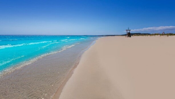 Een strand met helder turquoise water en een zandstrand.