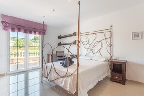 Ein Bett mit Baldachin, ein Holzbettrahmen, ein Nachttisch, ein Fenster mit Blick und ein Balkon.