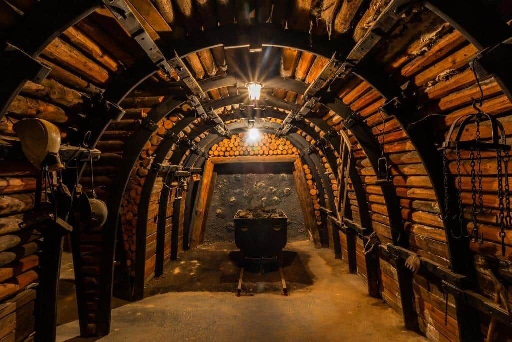 Un túnel arqueado con paredes de madera, una chimenea central y una lámpara colgante.
