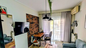 Ein kompakter Wohnbereich mit Essplatz, einer Couch, einem Fernseher und einer Ziegelwand.