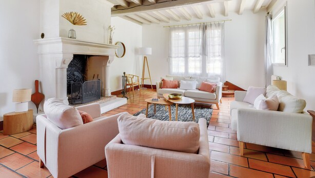 Uma sala de estar ampla com lareira, dois sofás, uma mesa de centro e uma janela grande com cortinas.