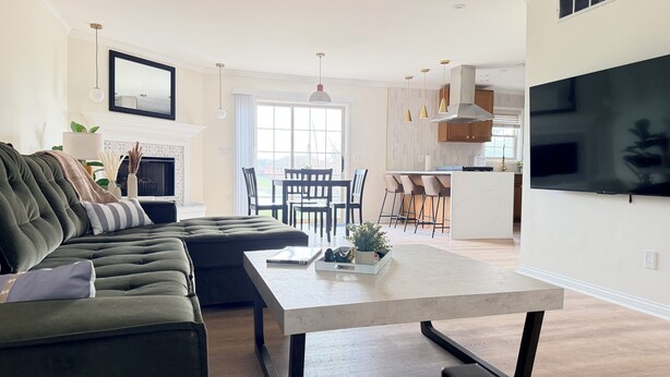 A modern living room with a sofa, a coffee table, and a TV mounted on the wall. - Shoreham Luxe - Vibrant 4BR\2.5BA with Waterfront (Evansville)