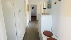 Ein schmaler Gang mit weißer Wand, Holzboden und einer weißen Theke mit zwei runden Hocker.