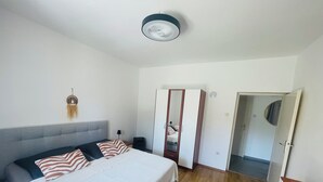 Ein Schlafzimmer mit einem Bett, einem Kleiderschrank, einem Spiegel und einer Deckenleuchte.