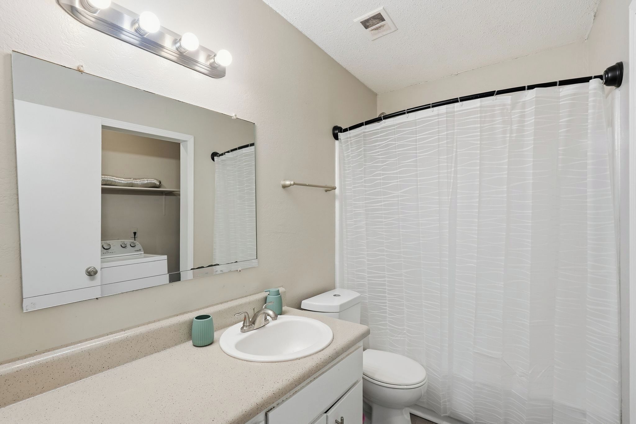 Un baño con lavamanos, espejo y retrete blancos.