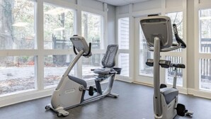 Une salle de sport équipée de deux appareils d’exercice, dotée de grandes fenêtres et offrant une vue sur l’extérieur.