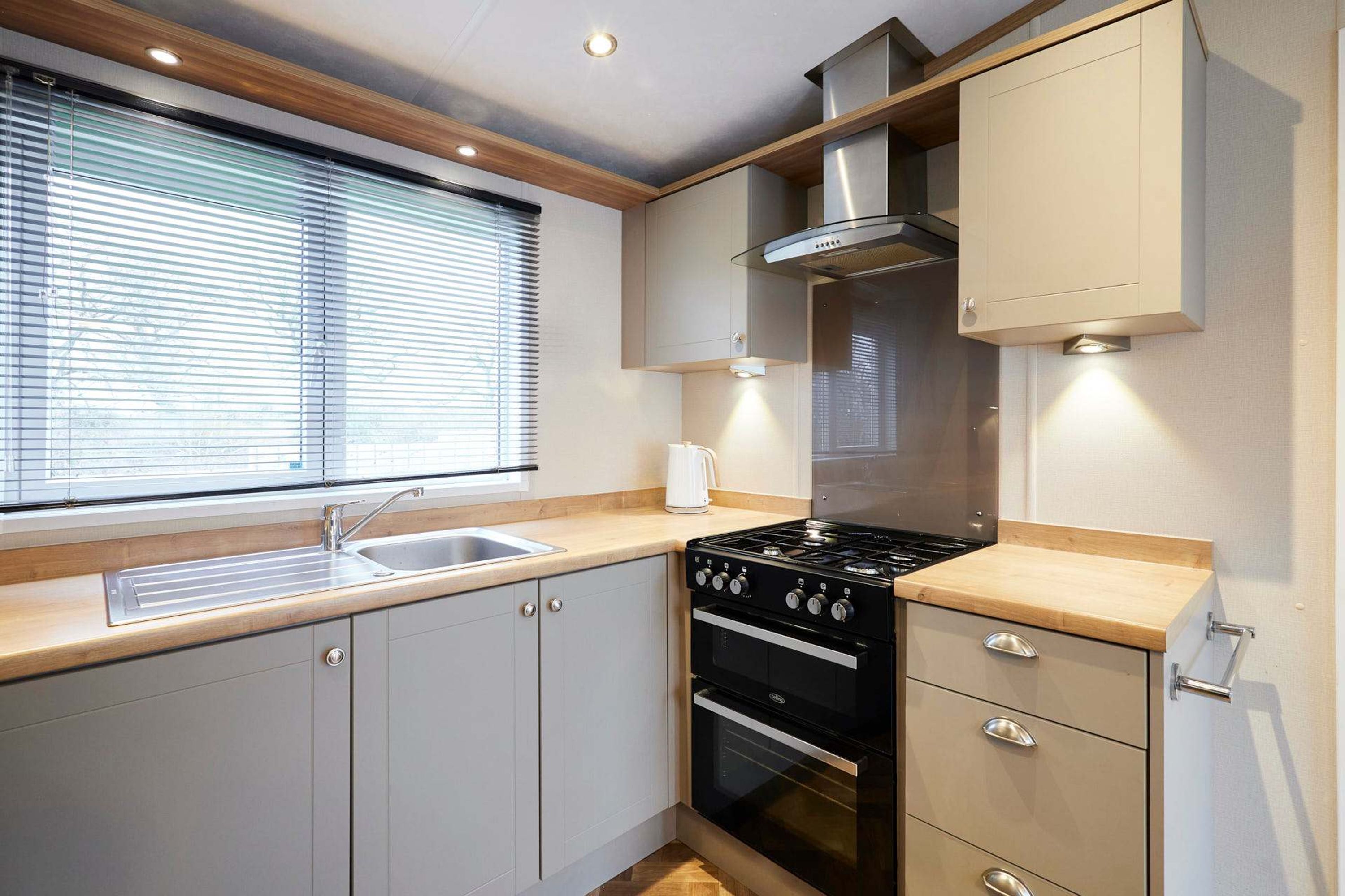A compact kitchen with a sink, stove, oven, and cabinets.