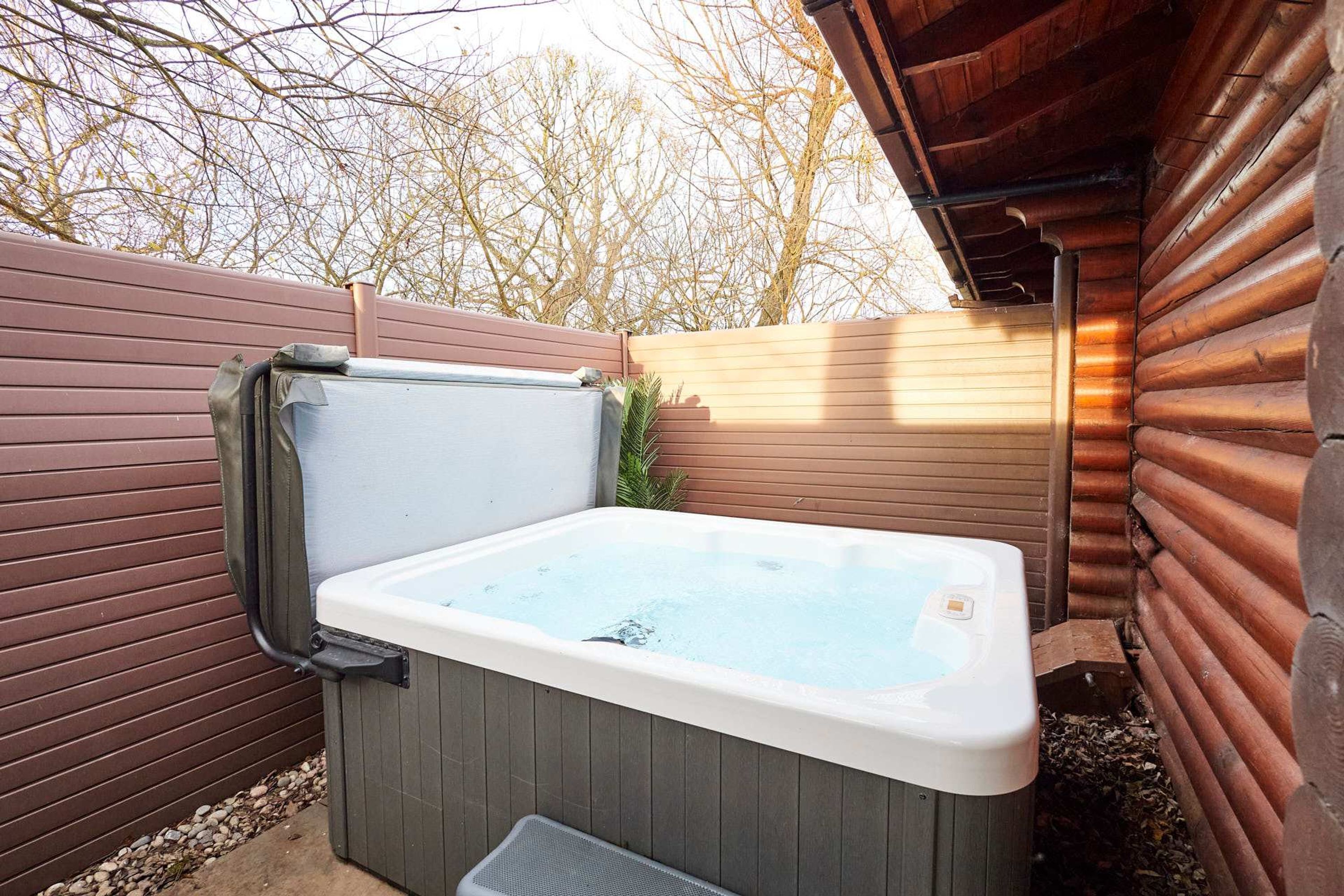 A hot tub in an outdoor setting with a wooden deck and a wooden fence.