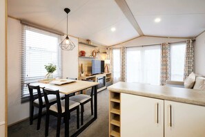 Een kleine keuken met een eettafel, stoelen en een televisie.
