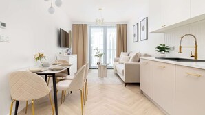 Moderni keittiö, jossa on ruokailutila, kalanruotokuvioinen lattia, taulutelevisio ja sisäänrakennettu uuni.