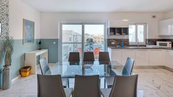 Un appartamento moderno con zona pranzo, cucina e un balcone con vista sulla città.