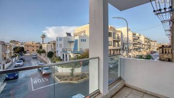 Un balcone con vista su una strada residenziale, un segnale di stop e cielo sereno.