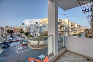 A balcony with a view of a residential street, a stop sign, and a clear sky. - Swieqi, Central 3BR home w/Fast WIFI Comfy Beds (Swieqi)