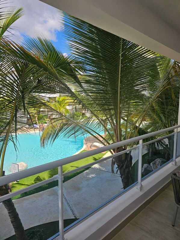 Vista da un balcone su una piscina circondata da palme.