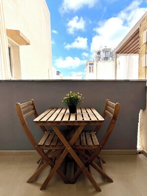 A wooden table with chairs on a balcony with a view of buildings. - Monte Napa Moments (Ayia Napa)