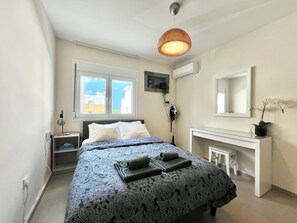 A bedroom with a bed, bedside table, nightstand, dresser, mirror, and window. - Monte Napa Moments (Ayia Napa)