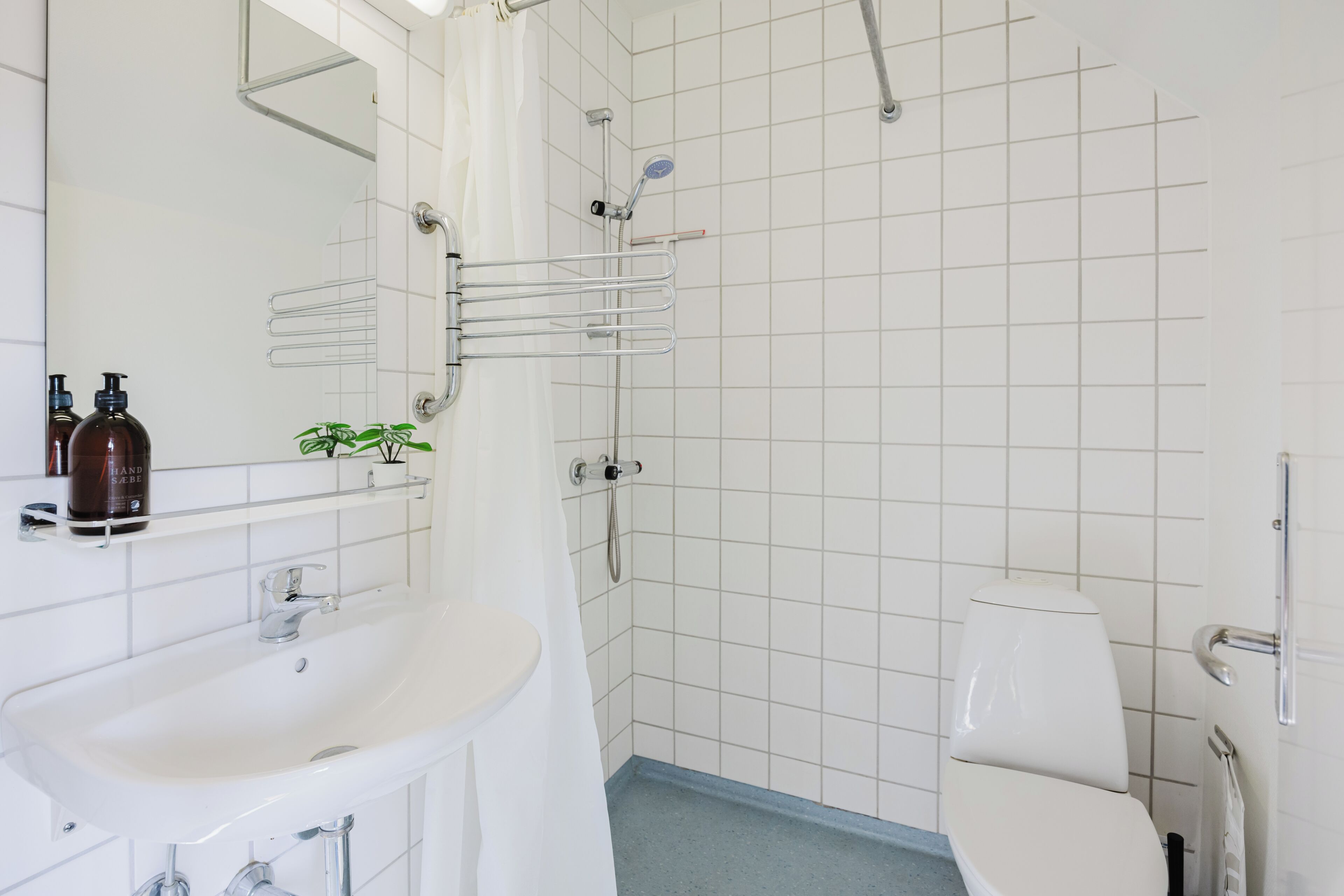 Un baño con lavamanos, espejo y ducha blancos.