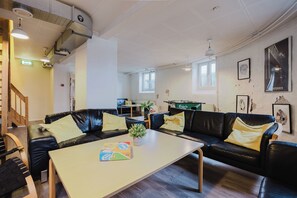 Un salon moderne avec un canapé en cuir noir, une table basse en bois et une petite plante en pot.