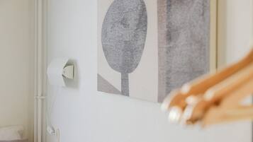 Detalle de una pared blanca con una obra de arte enmarcada, una puerta blanca y un picaporte blanco.