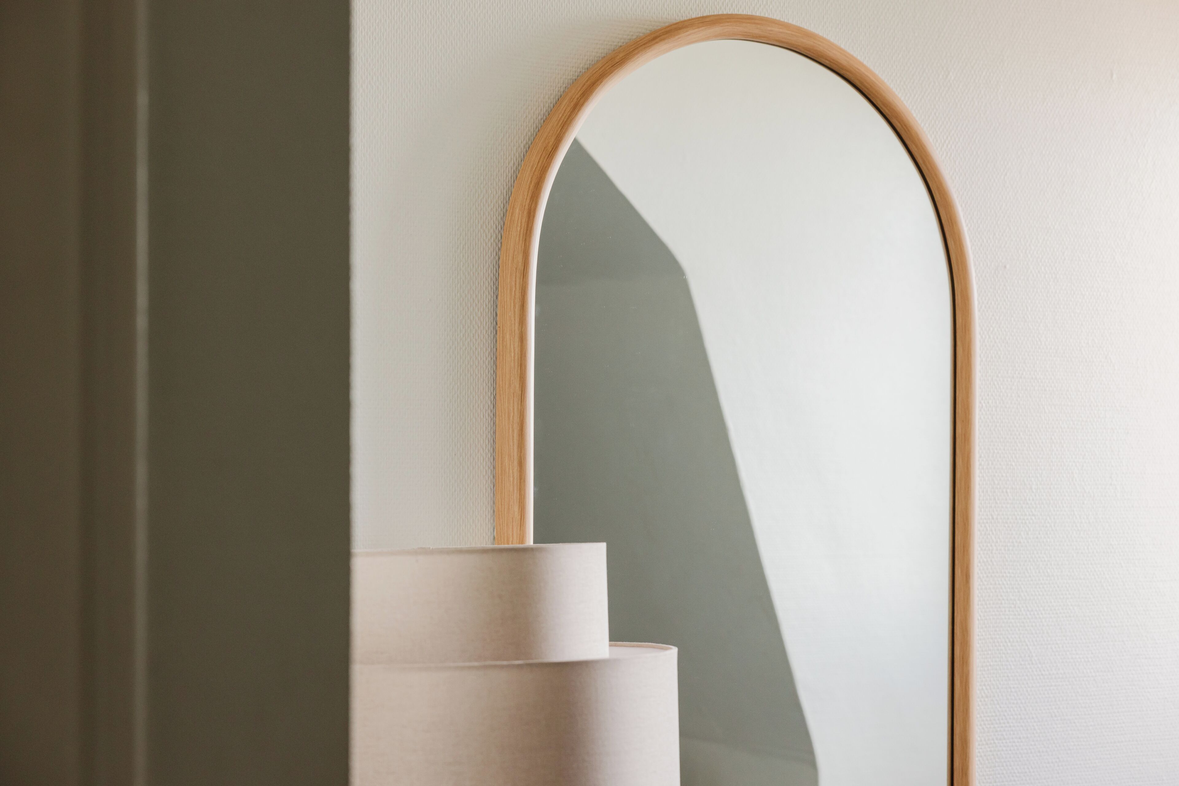 A mirror with a wooden frame mounted on a wall.