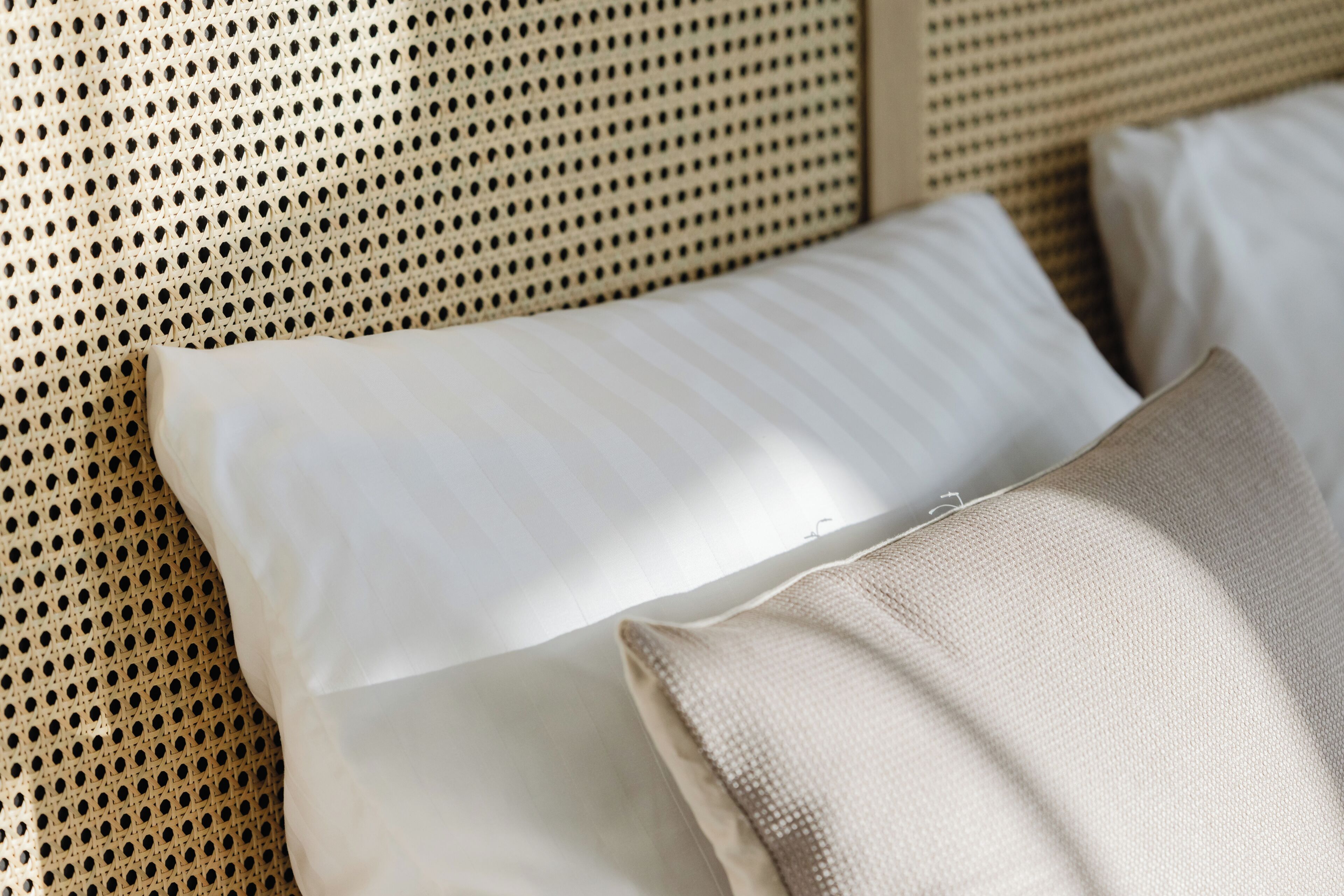 Un letto con testiera intrecciata e due cuscini.