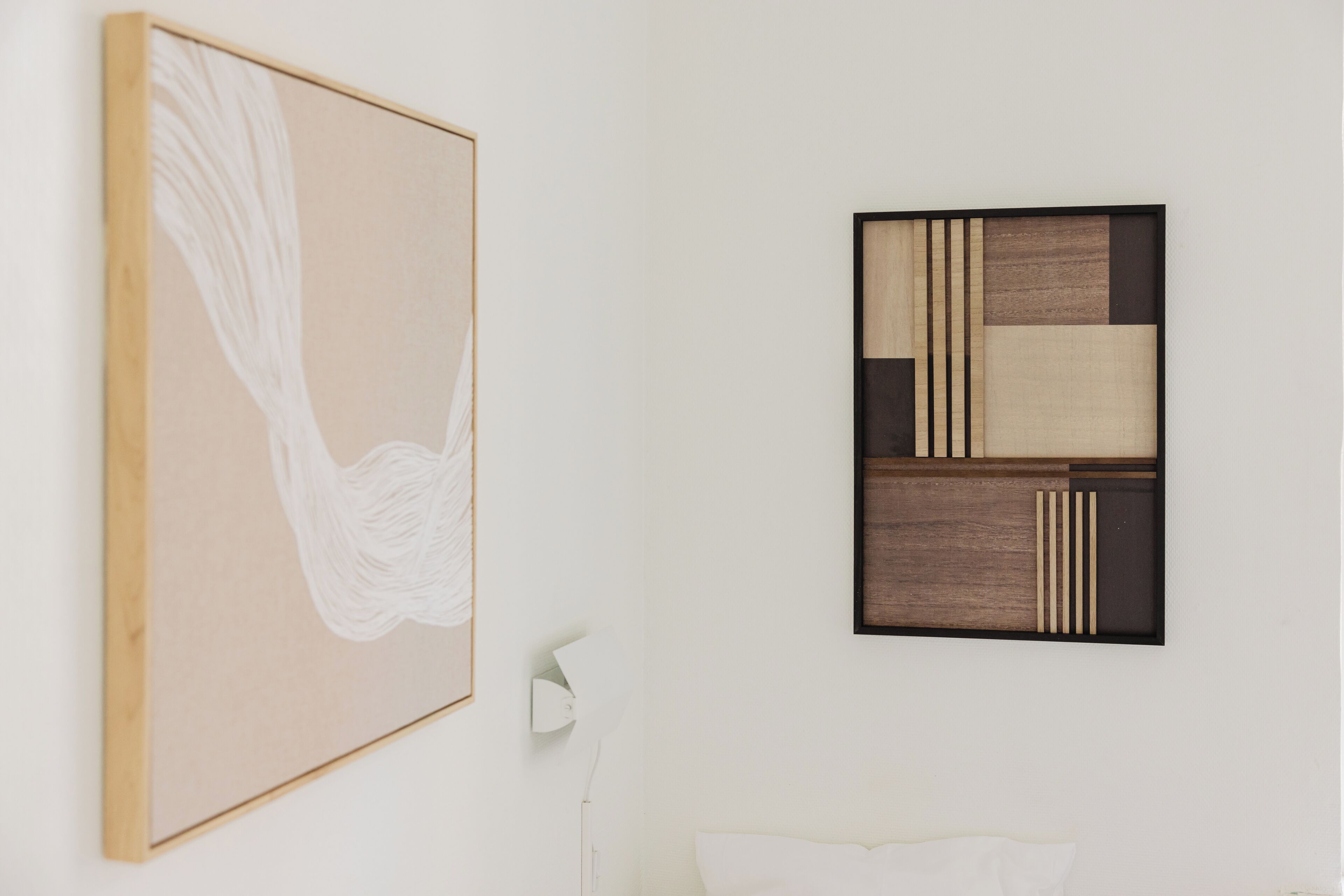A room with a large abstract painting, a geometric art piece, and a bedside lamp.