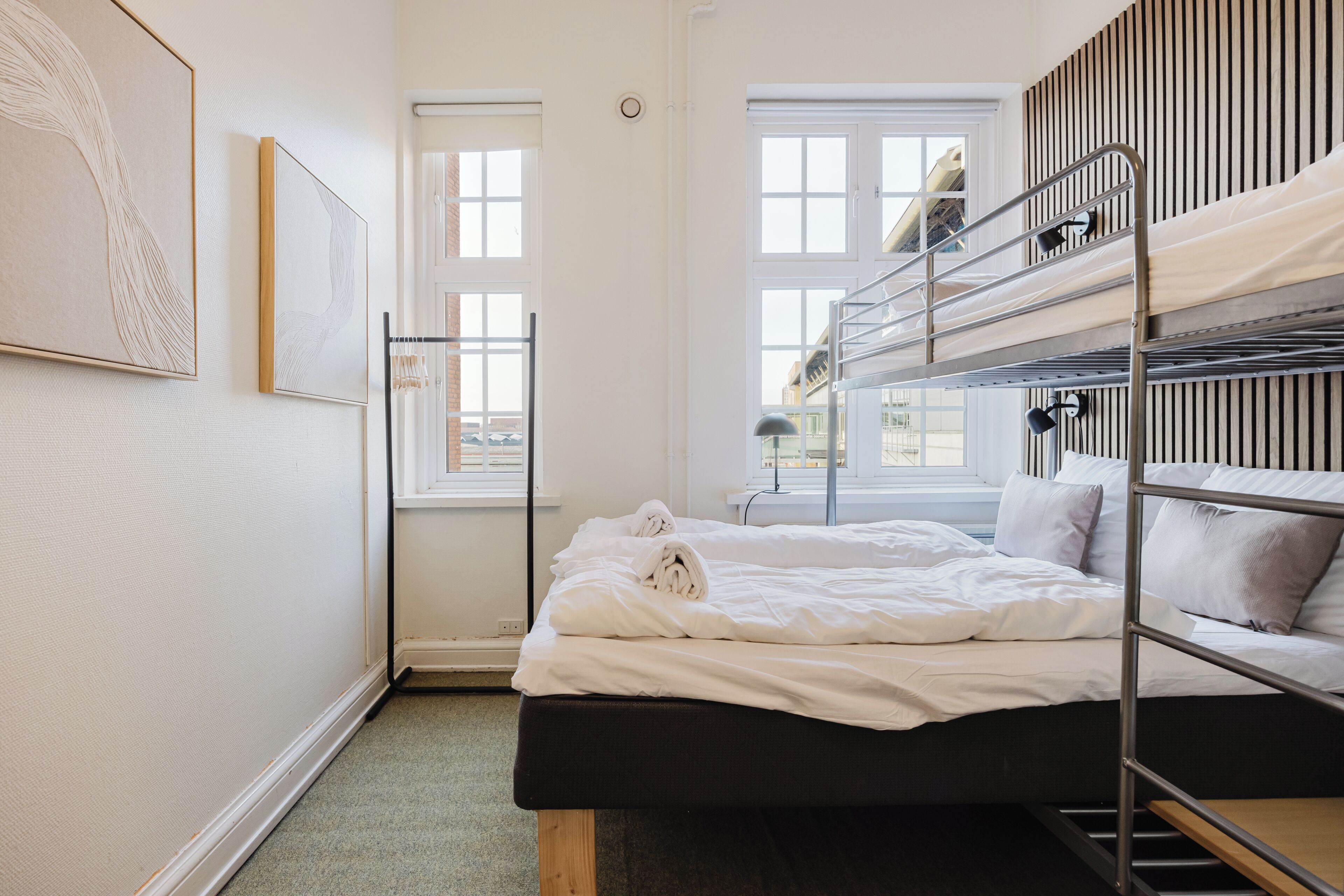 A bunk bed room with a window, a wall-mounted lamp, and a framed picture.